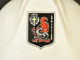 a white vase with a red and black emblem on it