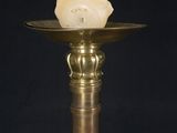a close up of a candle on a brass plate with a black background