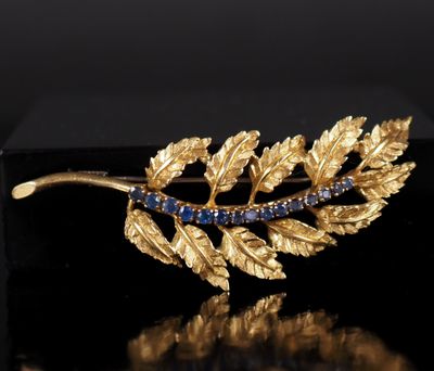 un gros plan sur une broche en feuille d'or sertie de pierres bleues