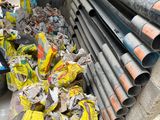 a pile of pipes sitting on a pallet next to a pile of bags