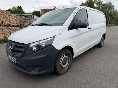 La camionnette blanche est garée sur le parking, à côté d'un tas de bois.