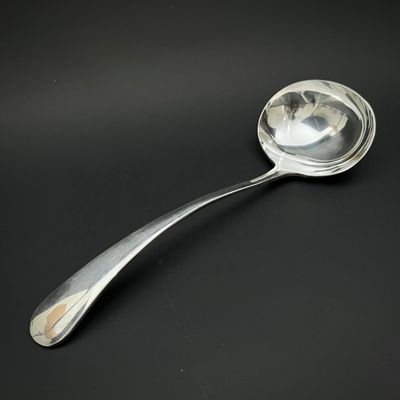 une cuillère en argent dont le manche repose sur une surface noire
