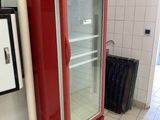 un réfrigérateur rouge posé au milieu d'un sol carrelé