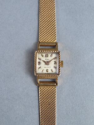a close up of a watch on a table with a blue background