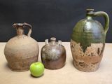 three vases sitting on a table next to a green apple