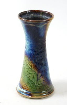 un vase bleu et vert posé sur une surface blanche