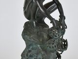 statue en bronze représentant un garçon assis sur un rocher, les mains posées sur les genoux