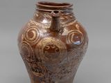 un vase marron orné d'un motif sur un fond gris