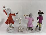 three figurines of people in different colors and sizes on a white background