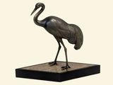 une statue représentant une grue posée sur un socle