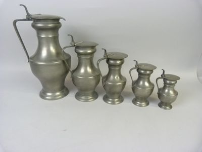 cinq vases en argent posés les uns à côté des autres sur une table