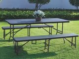 une table et des bancs posés dans l'herbe, sur lesquels trône un vase de fleurs