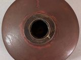 a brown vase with a hole in it on a white surface