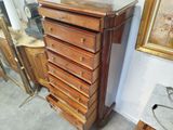 a tall wooden chest of drawers with a mirror on top of it