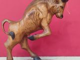 statue of a bull on a wooden base against a red wall