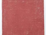 an old book with a red cover sitting on a white surface