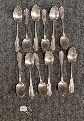 six cuillères en argent sont disposées en rang sur une surface grise