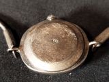 a silver watch that is sitting on a black cloth