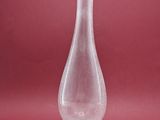 un vase en verre transparent posé sur un socle, sur un fond rouge