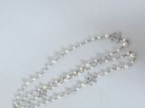 a close up of a necklace with pearls on a white surface