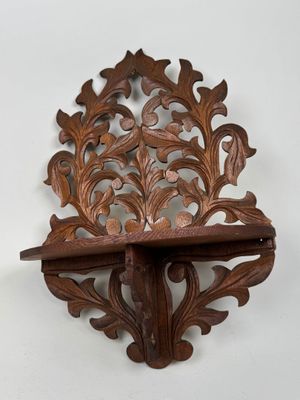 carved wooden shelf with a decorative design on top of it