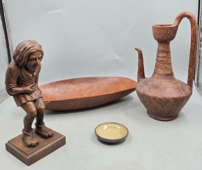 une statue représentant un homme assis à côté d'un bol et d'un vase