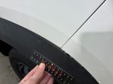 a hand that is holding a ruler next to a car