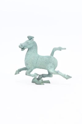 une petite statue représentant un cheval au galop sur un fond blanc