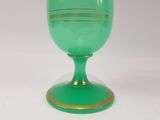 a green glass with a gold rim sitting on a white surface