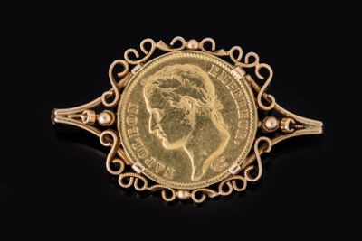 un gros plan d'une pièce d'or sertie dans une broche, sur fond noir