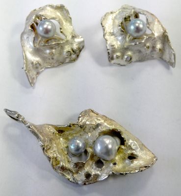 three pieces of silver and pearl jewelry sitting on a white surface