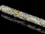 un stylo argenté orné d'inscriptions dorées, posé sur une surface noire