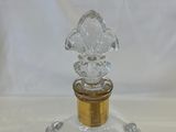 a clear glass bottle with a gold top on a white table