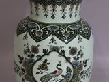 a white vase with a peacock on it on a table