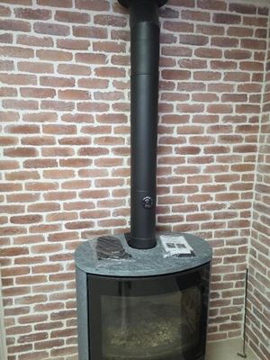 un poêle noir posé devant un mur de briques