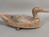un vieux canard en bois posé sur une surface grise