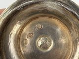 someone is holding a silver vase with a hole in it
