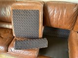 a brown leather couch with a seat cushion and a remote control