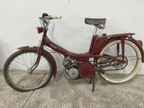 a red bike that is parked next to a white wall