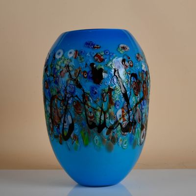 a blue vase sitting on a table with flowers on it