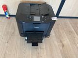 a canon printer sitting on top of a wooden floor next to a can of soda
