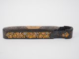 a close up of a black and gold case with flowers on it