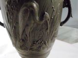 a black vase with a bird on it on a table