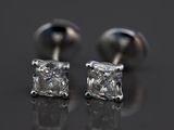 une paire de boucles d'oreilles en diamant posées sur une surface réfléchissante
