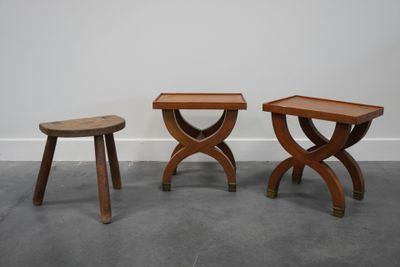deux petits tabourets en bois placés l'un à côté de l'autre sur un sol en béton