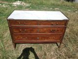une commode au plateau en marbre posée dans l'herbe