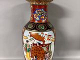 a vase with a painting on it sitting on a table