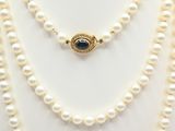 a white pearl necklace with a gold clasp on a mannequin