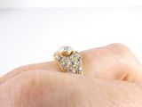 a woman ' s hand holding a gold ring with a diamond on it
