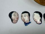 four ceramic figurines of women with different hair styles on a white surface